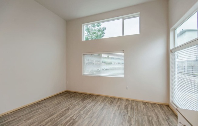 the spacious living room with large windows and wood flooring