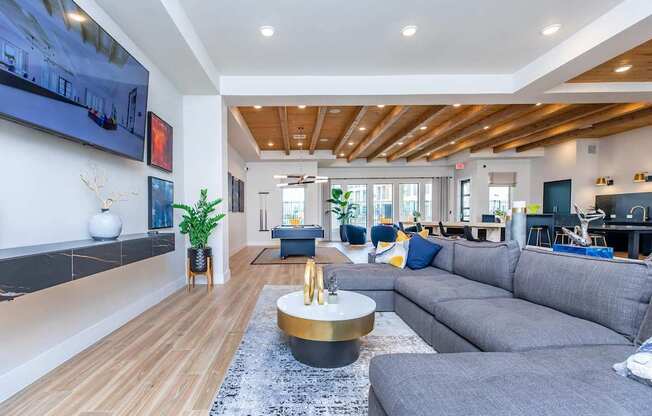 A modern living room with a grey sofa and a wooden ceiling.