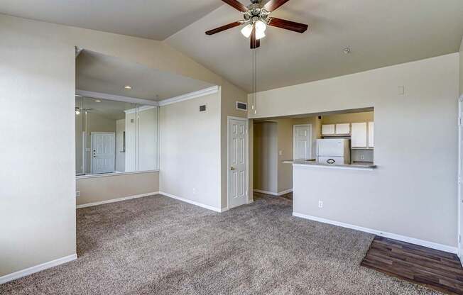 A spacious room with a ceiling fan and carpeted floor.
