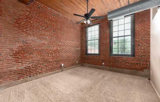 an empty room with a brick wall and a ceiling fan