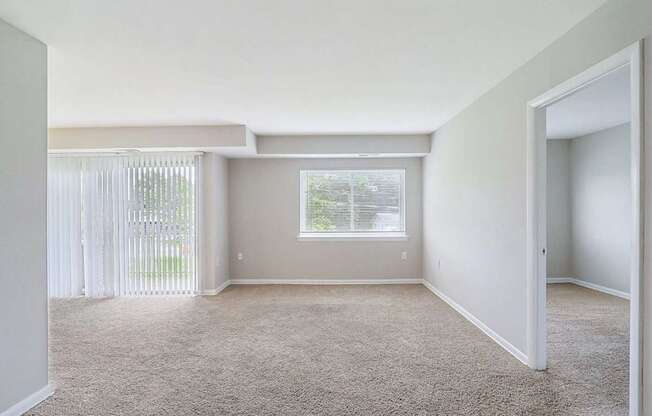 A room with a carpeted floor and a window with blinds.