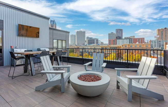 Rooftop deck with lounge seating and gas firepit overlooking park and skyline.