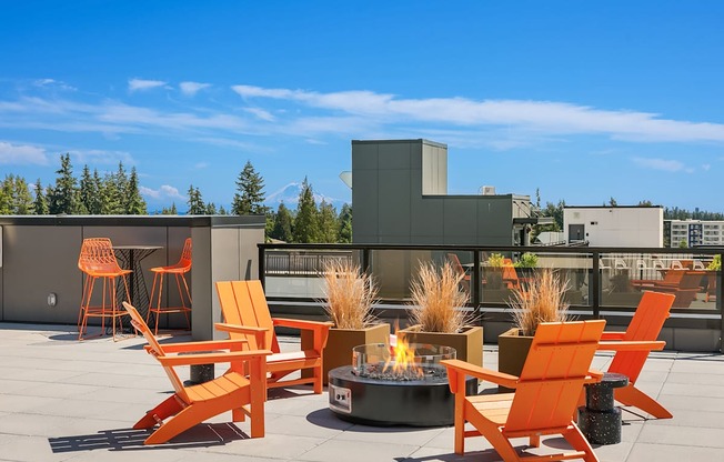 A patio with orange chairs and a fire pit.
