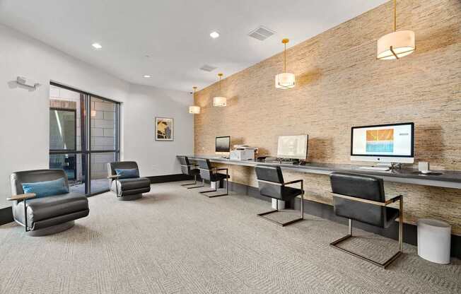 A modern office space with a brick wall and a long desk with chairs.