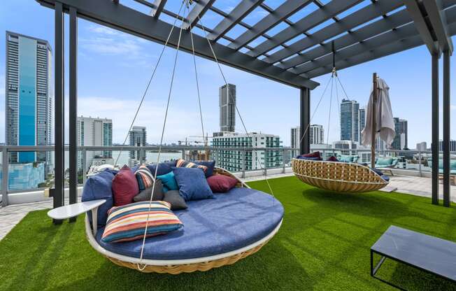 a lounge area with couches and chairs on a roof top with a view of the city