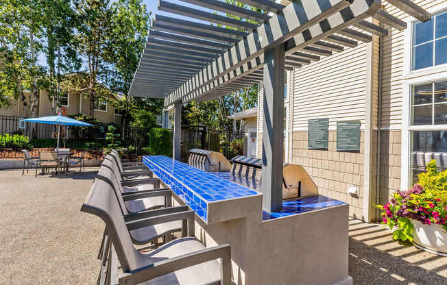 A patio with a blue table and chairs under a striped awning.