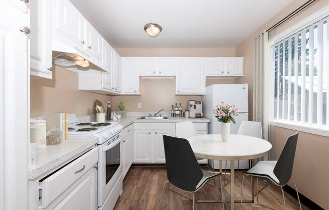 a kitchen with white cabinets and a white table and chairs