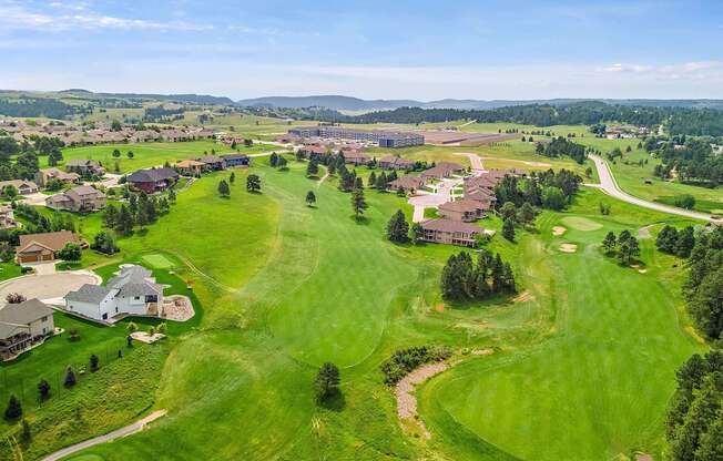 A golf course with a green lawn and a few buildings.