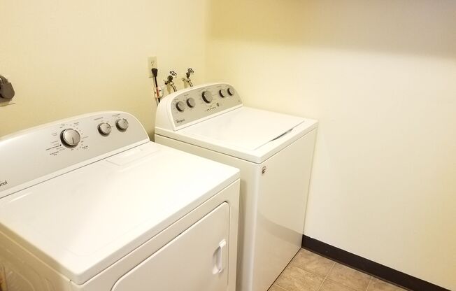 Two white front loading washing machines in a laundry room.
