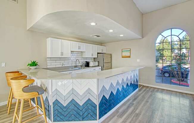 a kitchen with white cabinets and blue chevron tile