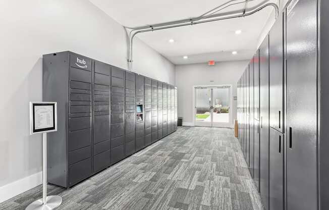 A hallway with a sign on a stand and a row of lockers on the wall.