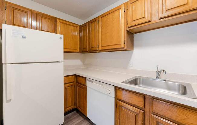 A white refrigerator stands in a kitchen with wooden cabinets.