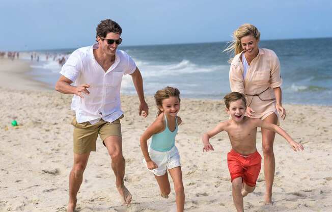 A family of four is running on the beach.