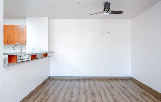 Empty room with wooden floor and ceiling fan.