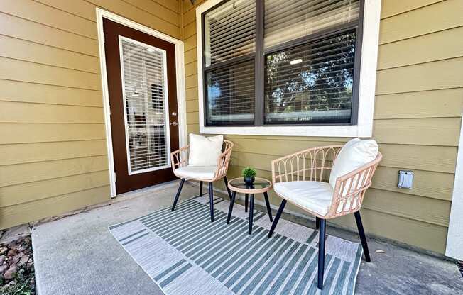 a front porch of a home with two chairs and a table