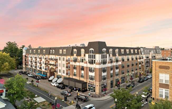 A large building with a lot of windows is surrounded by trees and cars.