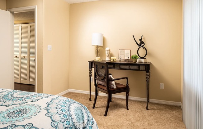 a bedroom with a desk and a door to a closet