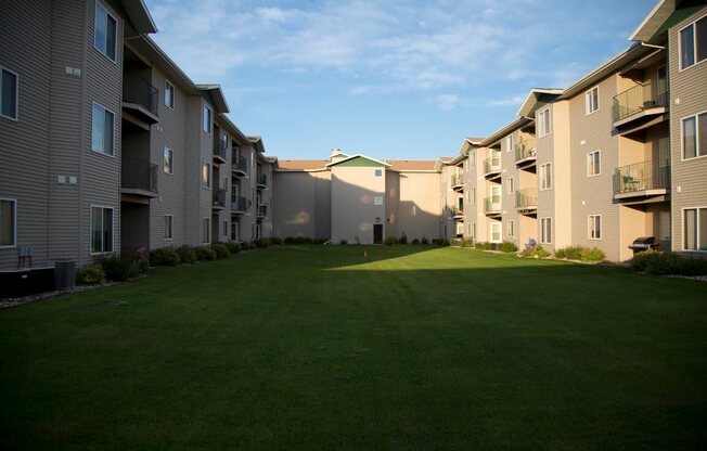 Lush grounds of Cottonwood Apartment Homes with sunlight shining on the patio and balconies.