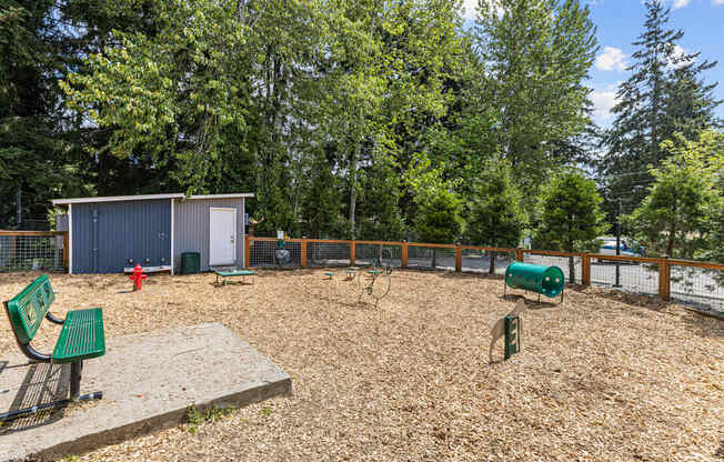 A playground with a green bench and a brown sandbox.