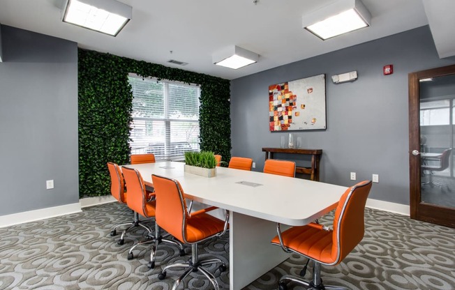 a conference room with a white table and orange chairs