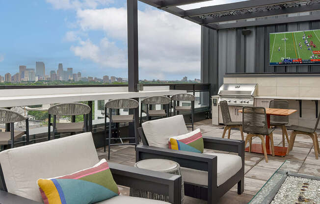 A patio with a couch and chairs overlooking a city skyline.