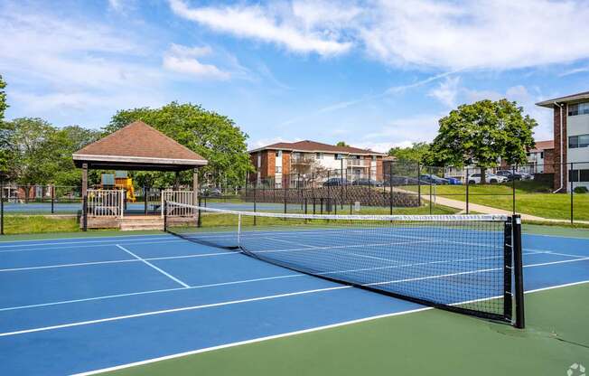 A tennis court with a blue surface and a black fence.
