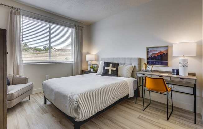 bedroom with decorated furnishings, wood tone floor, desk and window