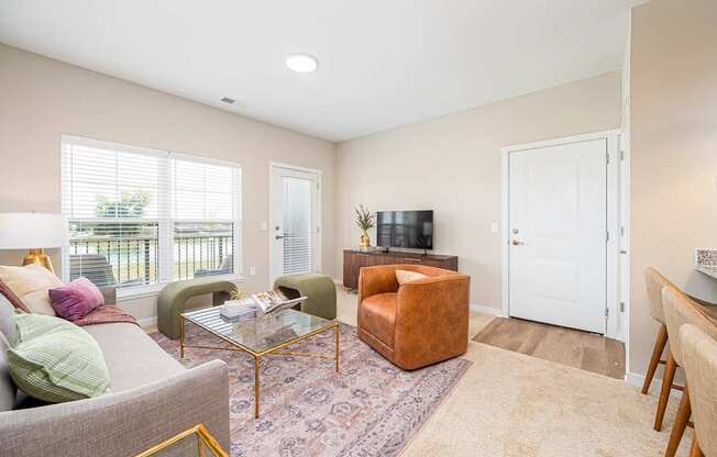 A living room with a grey couch, a brown chair, a glass coffee table, and a television.