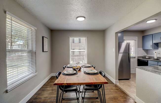 a dining room with a wooden table and chairs and a kitchen with stainless steel appliances