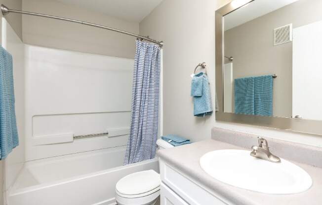 A white bathroom with a white toilet, white sink, and a white bathtub.