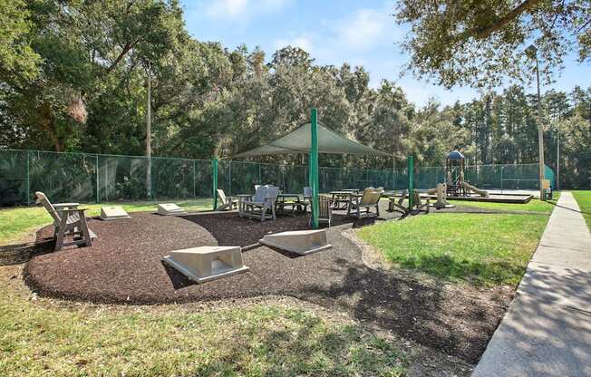A playground with a green canopy and a fence.