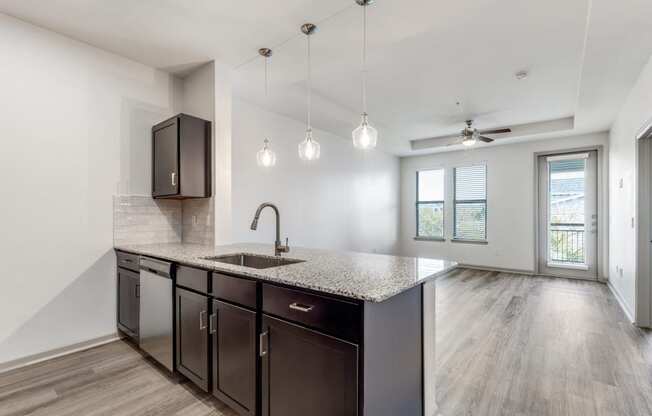 A kitchen with dark brown cabinets and a granite countertop.
