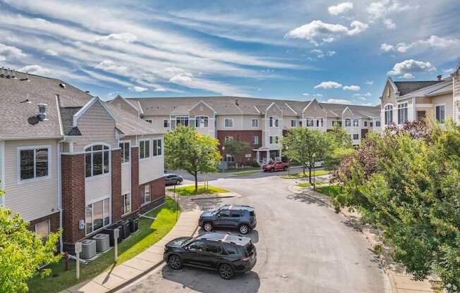 A black car is parked on a street in front of apartment buildings.