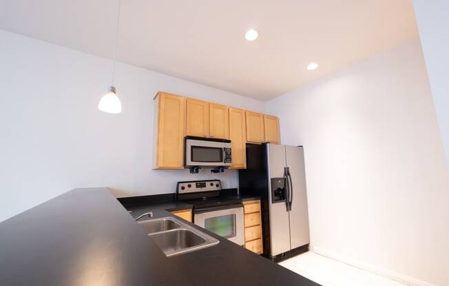 a kitchen with a black counter top and stainless steel appliances at 26 West, Managed by Buckingham Urban Living, Indianapolis