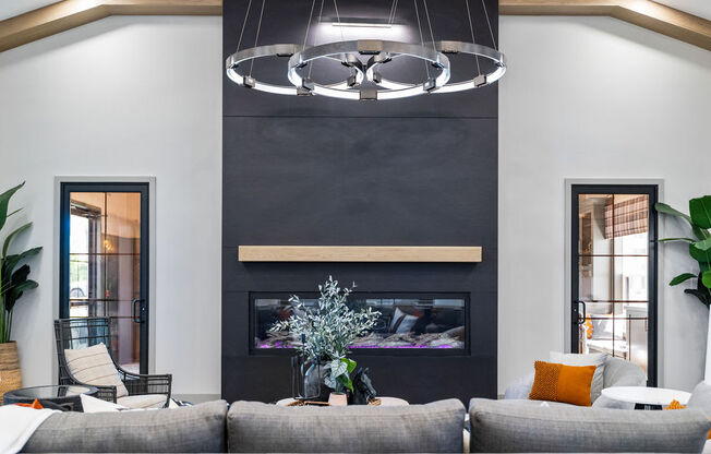 A modern living room with a grey sofa, a fireplace, and a hanging light fixture at Madison Prickett Preserve, Yardley Pennsylvania