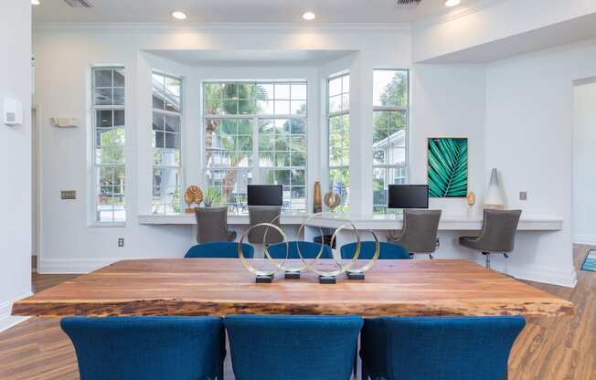 a large wooden table with blue chairs and a large window in the background