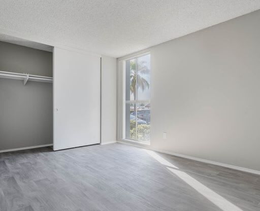 an empty living room with a window and a closet at The Arches Apartments, California, 92021