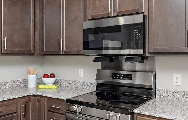 A kitchen with brown cabinets and a black microwave above a stove.