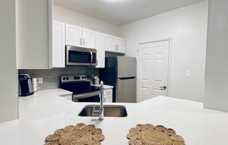 white kitchen with a sink and a microwave at Mainstreet Apartments, Florida, 33756