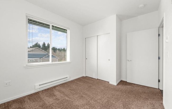 a bedroom with a large window and white walls