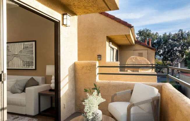 A balcony with a table and chairs overlooking a pool.