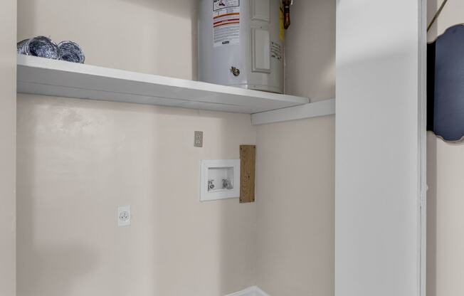 a room with a water heater and a shelf on the wall