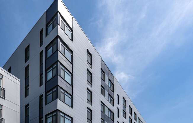 A modern building with a grey facade and a parking lot in front.