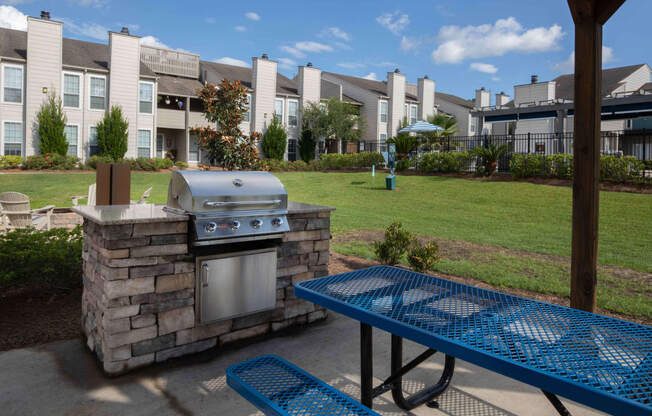 an outdoor grill and picnic table at the whispering winds apartments in pearland, tx