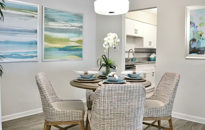 A dining room with a table set for four and two chairs.
