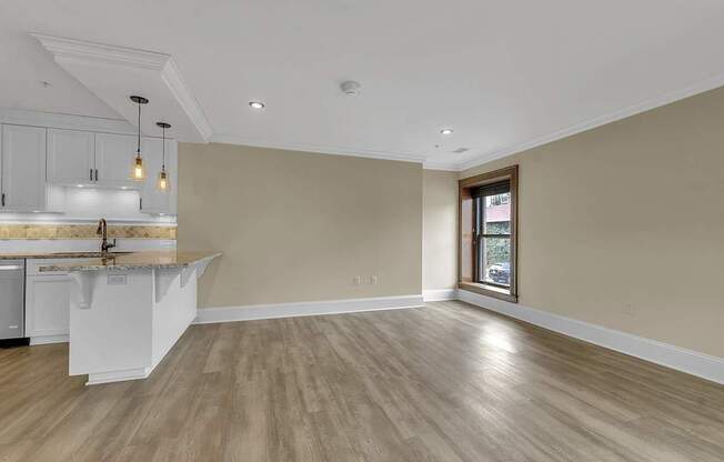 an empty living room with a kitchen and a window at The Knights @ 506 Delaware Apartments, Buffalo