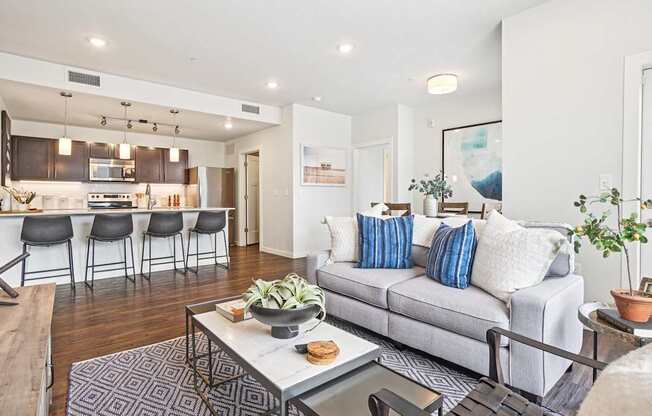 A modern living room with a grey couch and a coffee table. at Connect at First Creek Apartments, Colorado