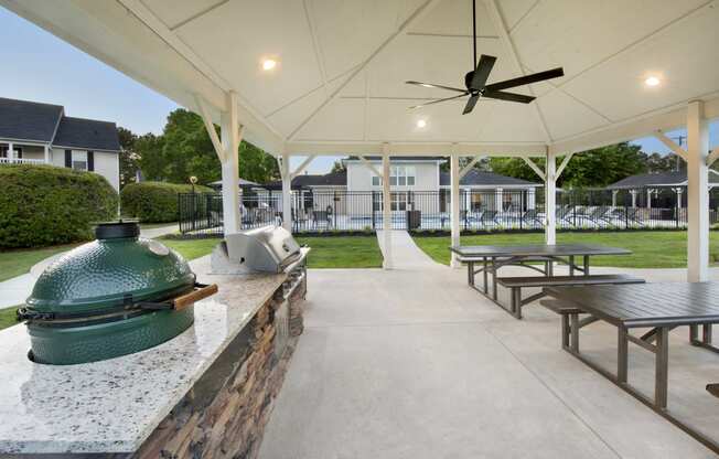 a patio with picnic tables and a grill and a ceiling fan