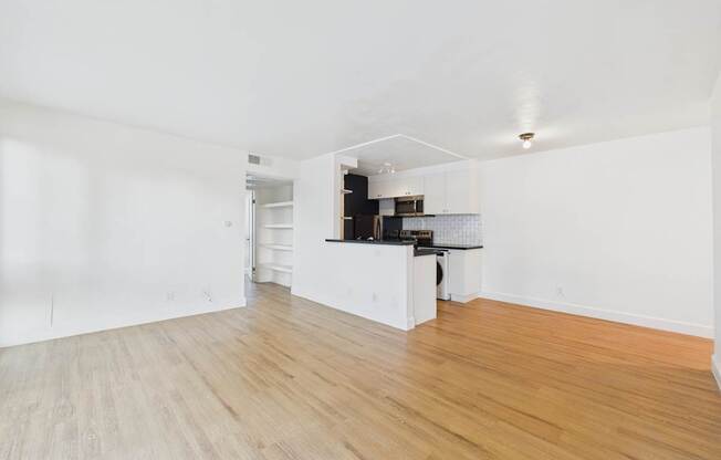 A kitchen area with white cabinets and a wooden floor.