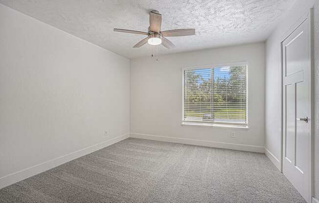 bedroom with a ceiling fan and a large window at The Crossings Apartments, Michigan, 49508